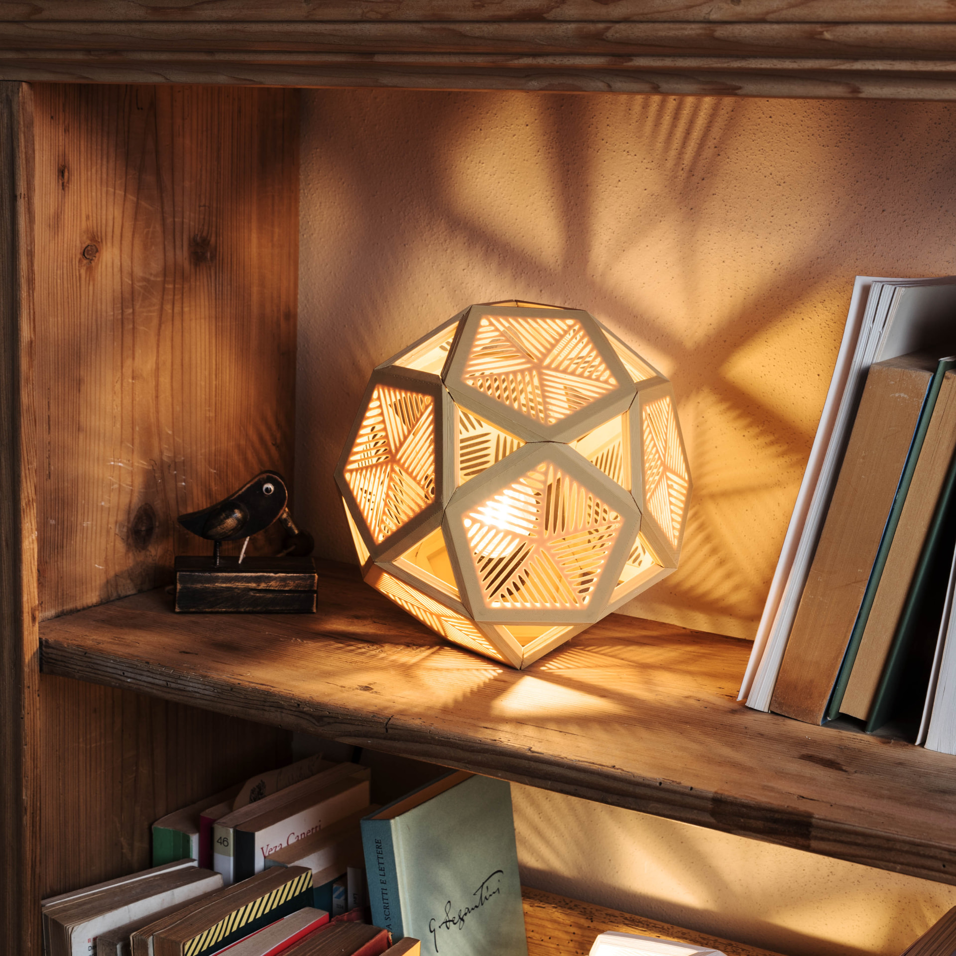 Lampada Pentade accesa su una libreria in legno
